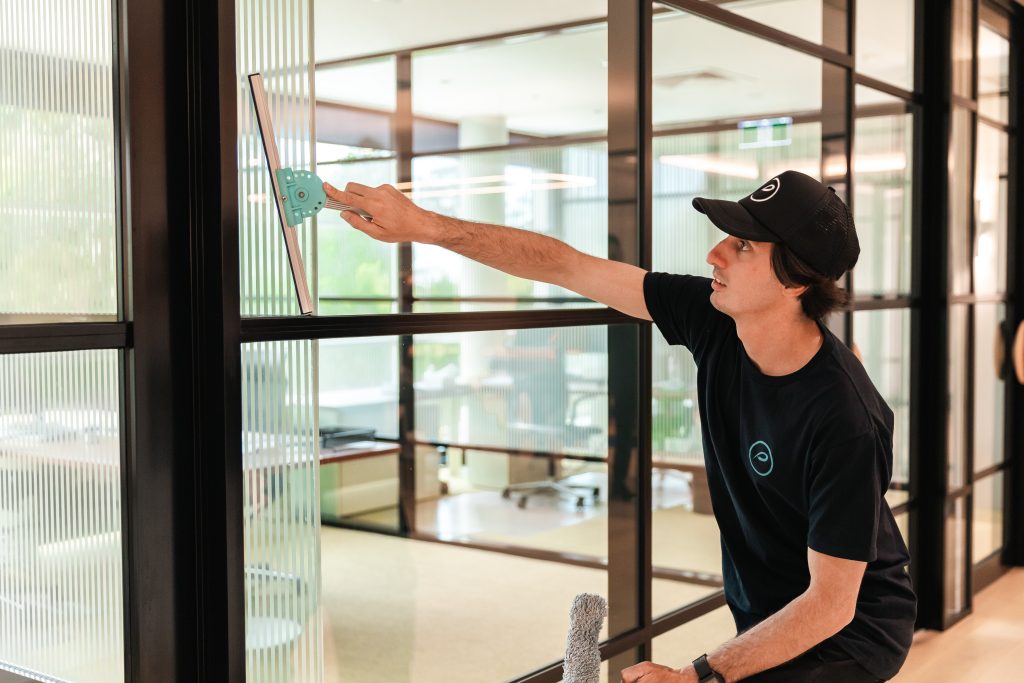 commercial cleaner cleaning windows in office